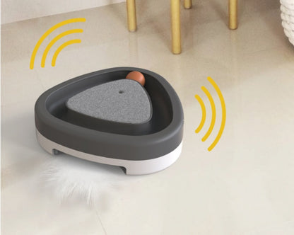 Interactive cat toy with feather and ball on floor, triangle-shaped design